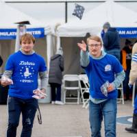 Two alums play cornhole at the tailgate